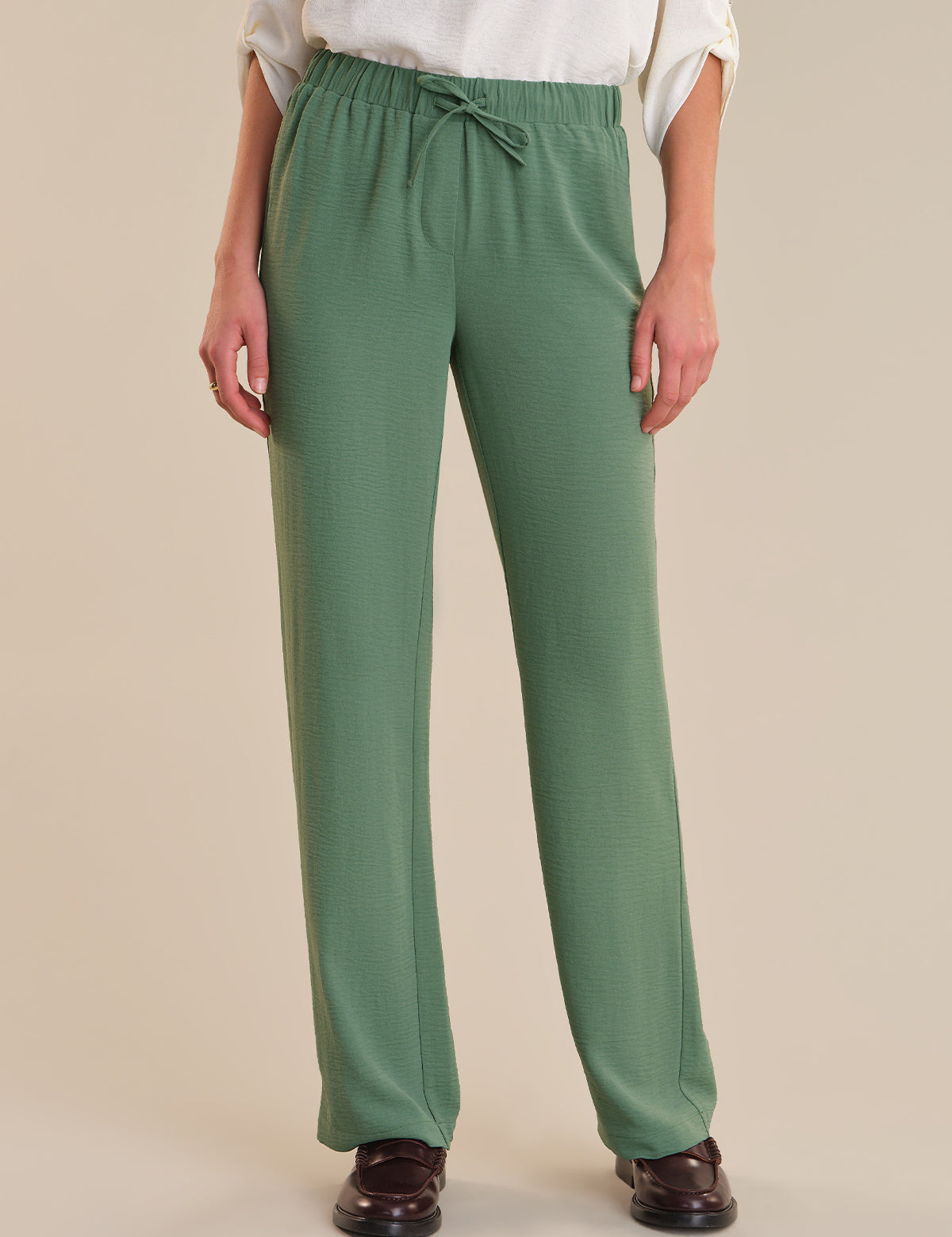 Green pants worn by a person on a beige background