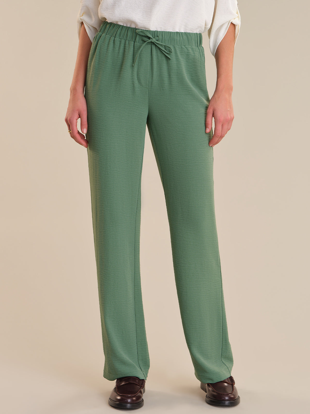 Green pants worn by a person on a beige background