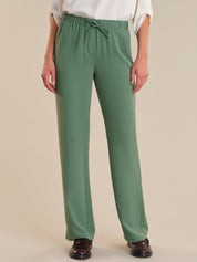 Green pants worn by a person on a beige background