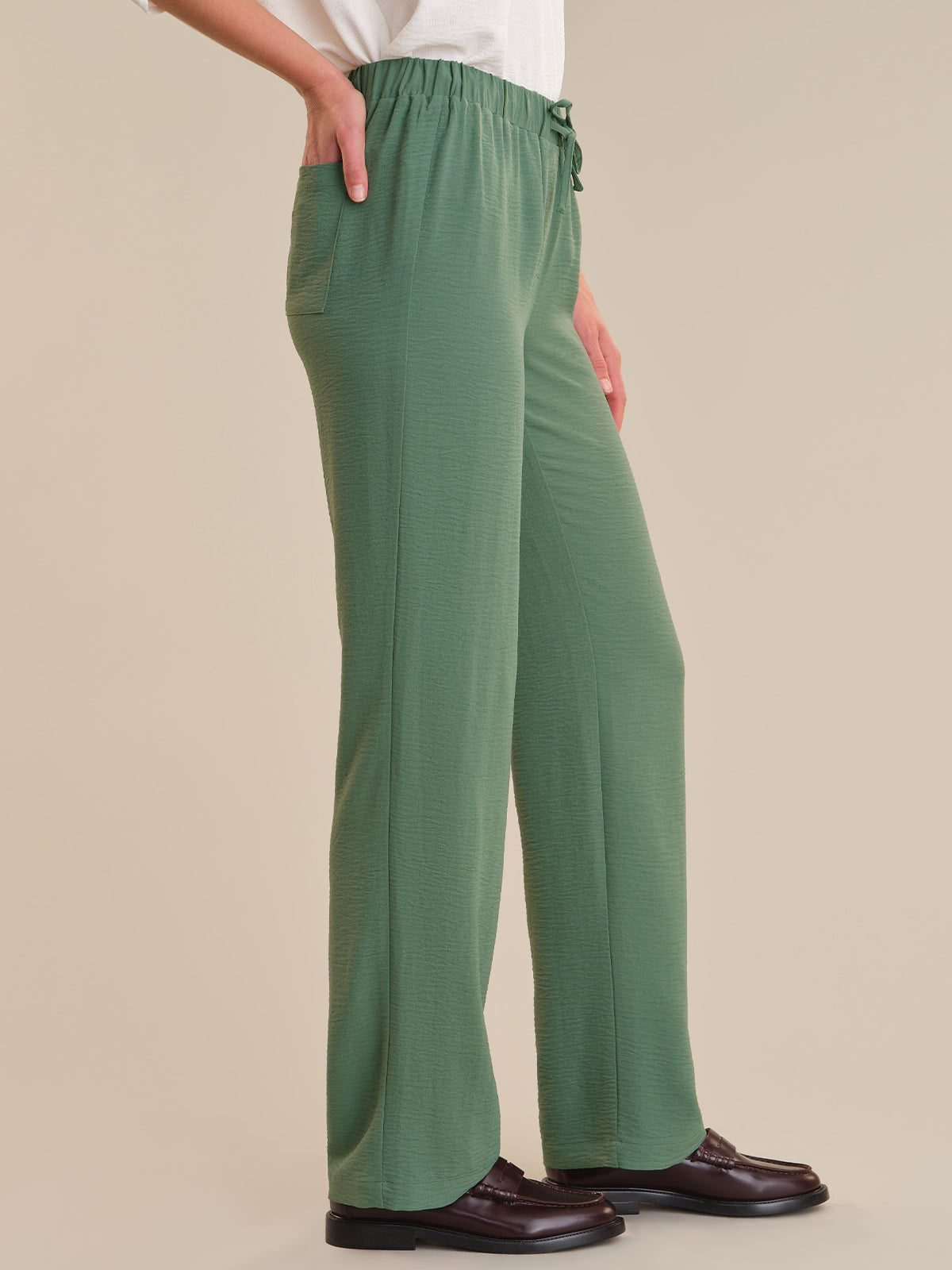 Green pants worn by a person on a beige background