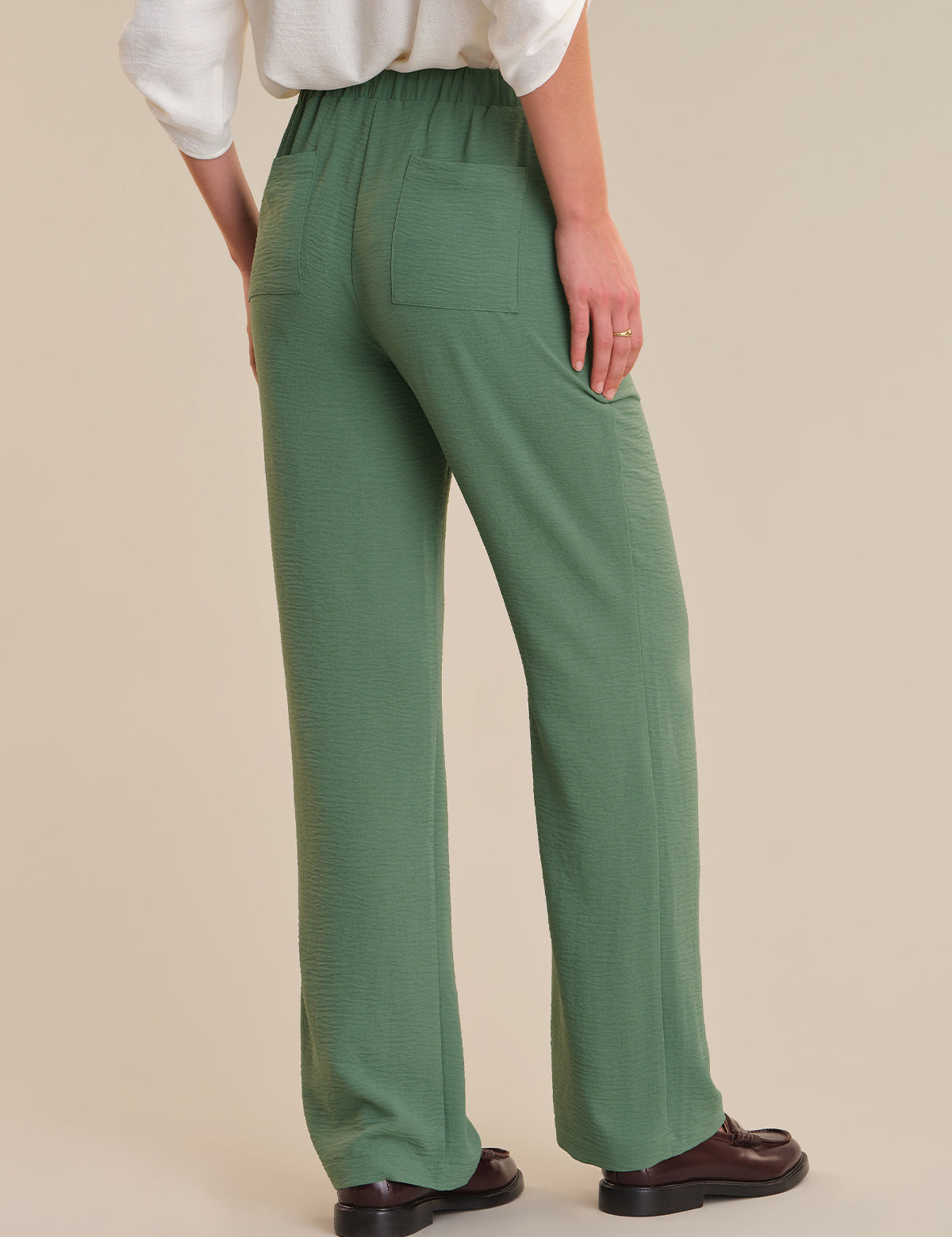 Person wearing green pants on a beige background