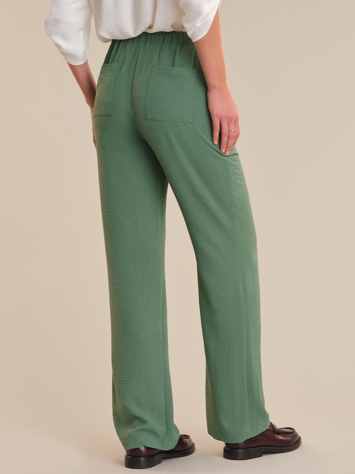 Person wearing green pants on a beige background