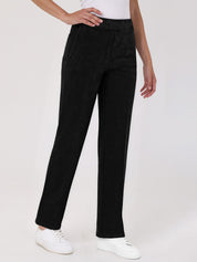 Person wearing black pants and white shoes on a plain background