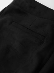 Close-up of black pants with a pocket detail on a white background