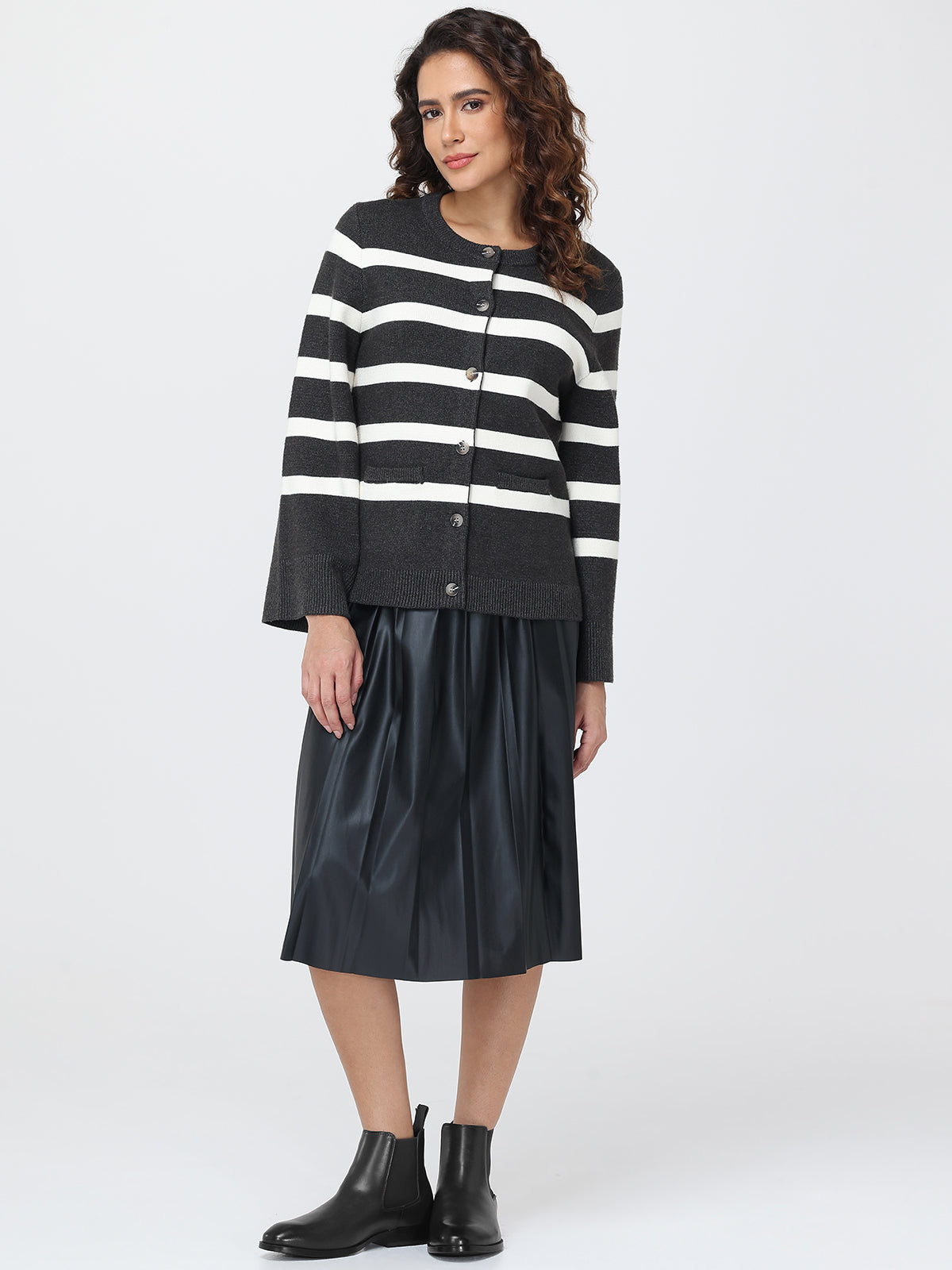 Woman wearing a black and white striped cardigan with a black leather skirt on a white background