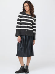 Woman wearing a black and white striped cardigan with a black leather skirt on a white background