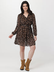 Woman wearing a leopard print dress with long sleeves and brown boots on a white background