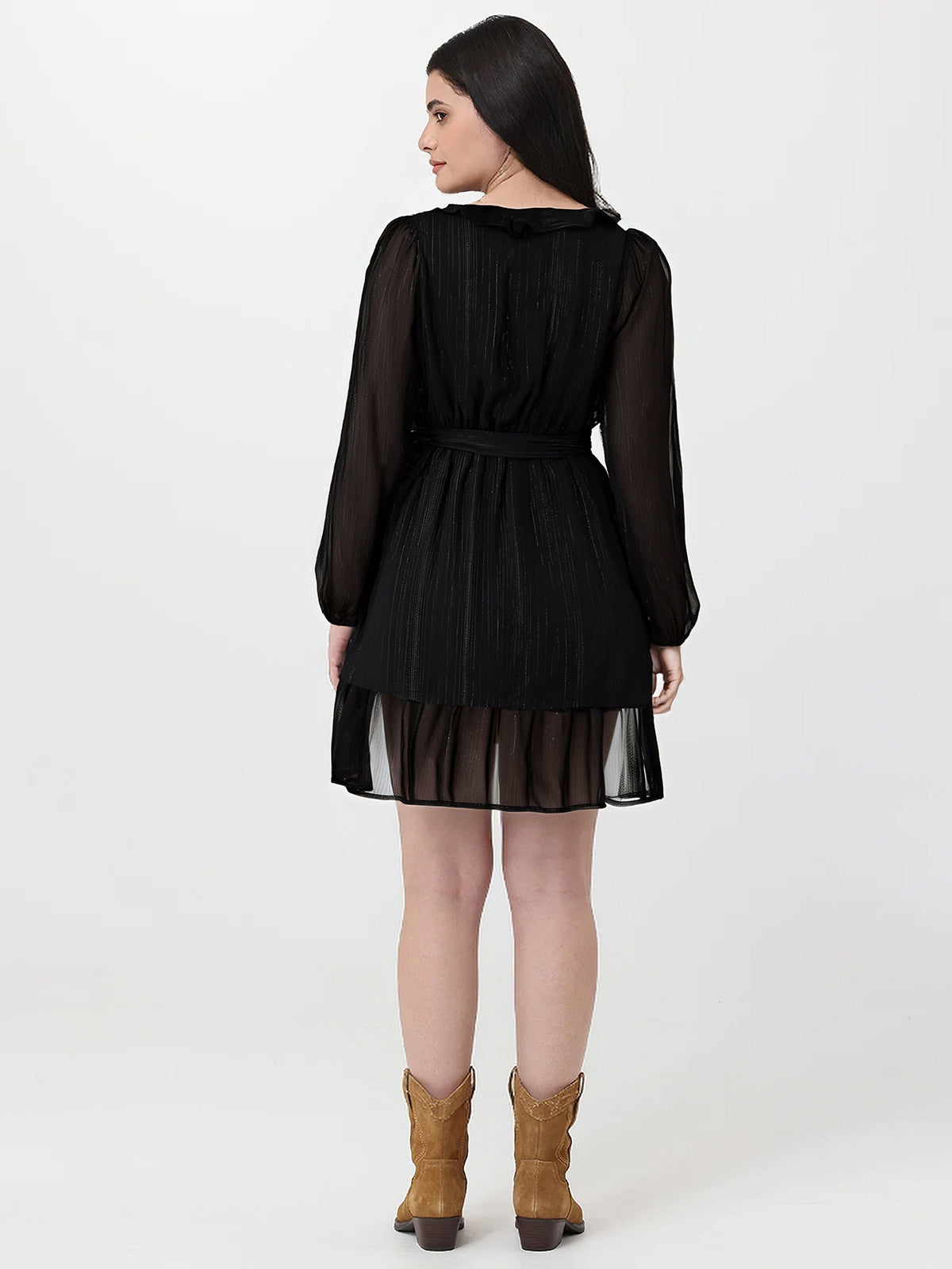 Woman wearing a black dress with sheer sleeves and skirt on a white background