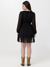 Woman wearing a black dress with sheer sleeves and skirt on a white background