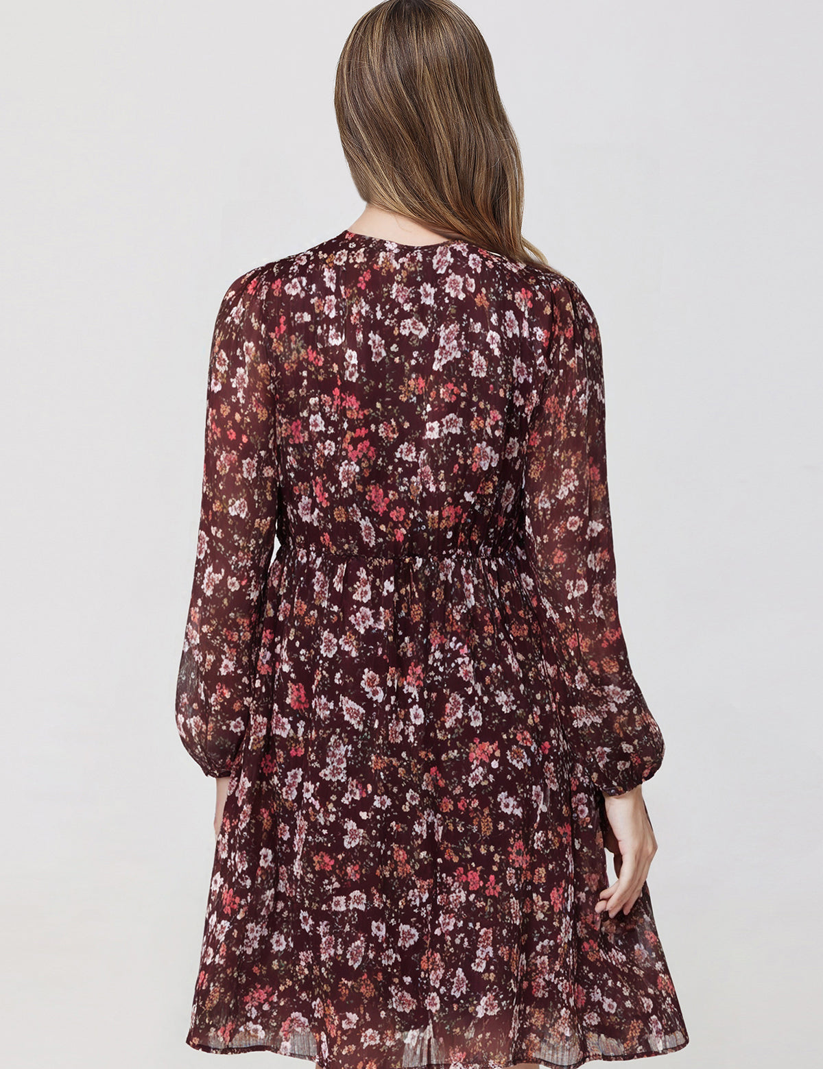 Woman wearing a floral dress with long sleeves on a plain background