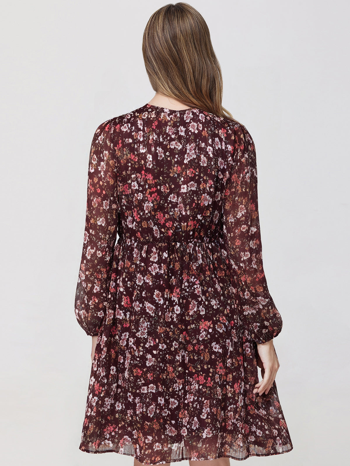 Woman wearing a floral dress with long sleeves on a plain background