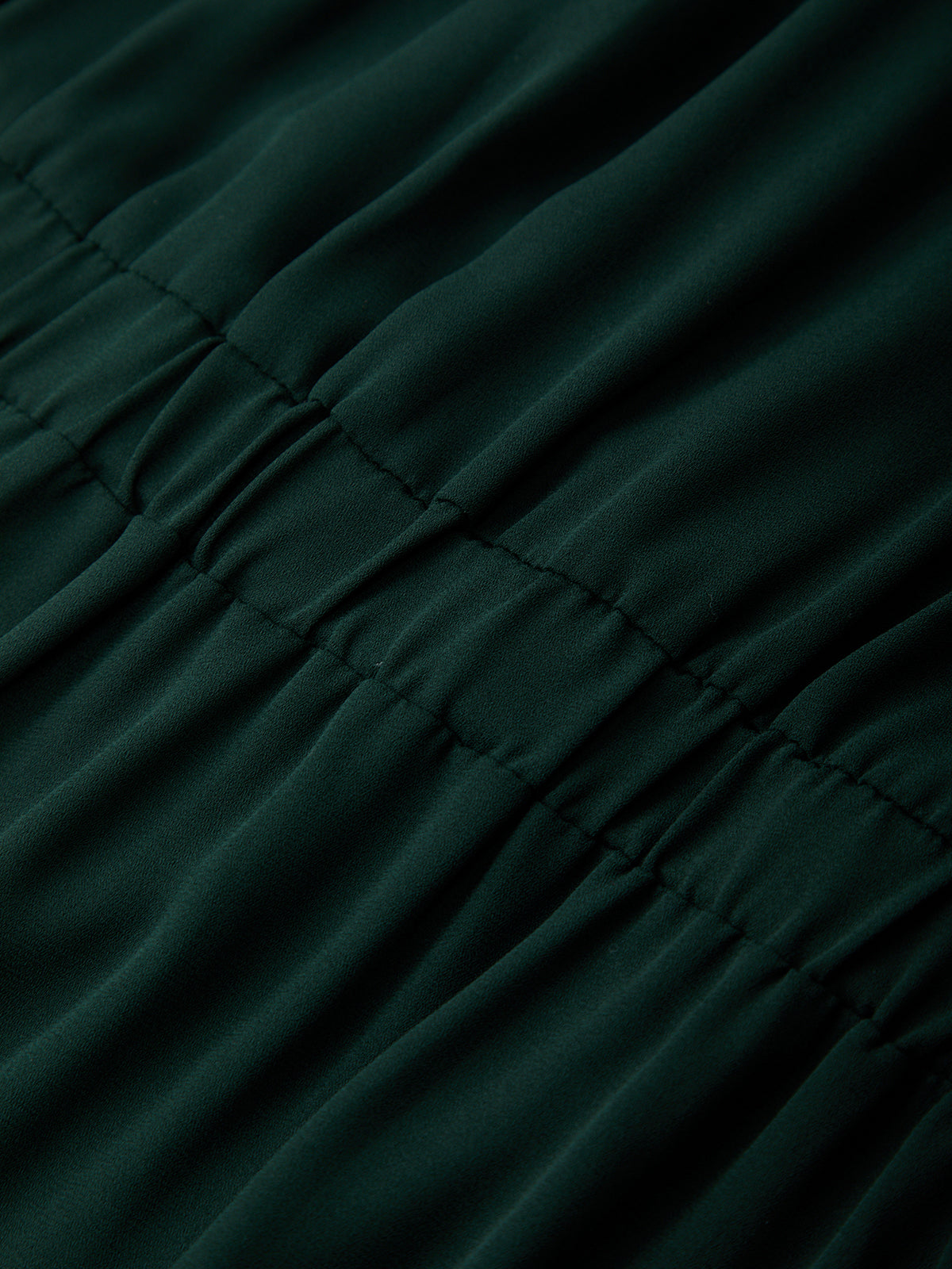 Close-up of dark green fabric with visible stitching