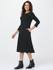 Woman wearing a black dress with 3/4 sleeves on a white background