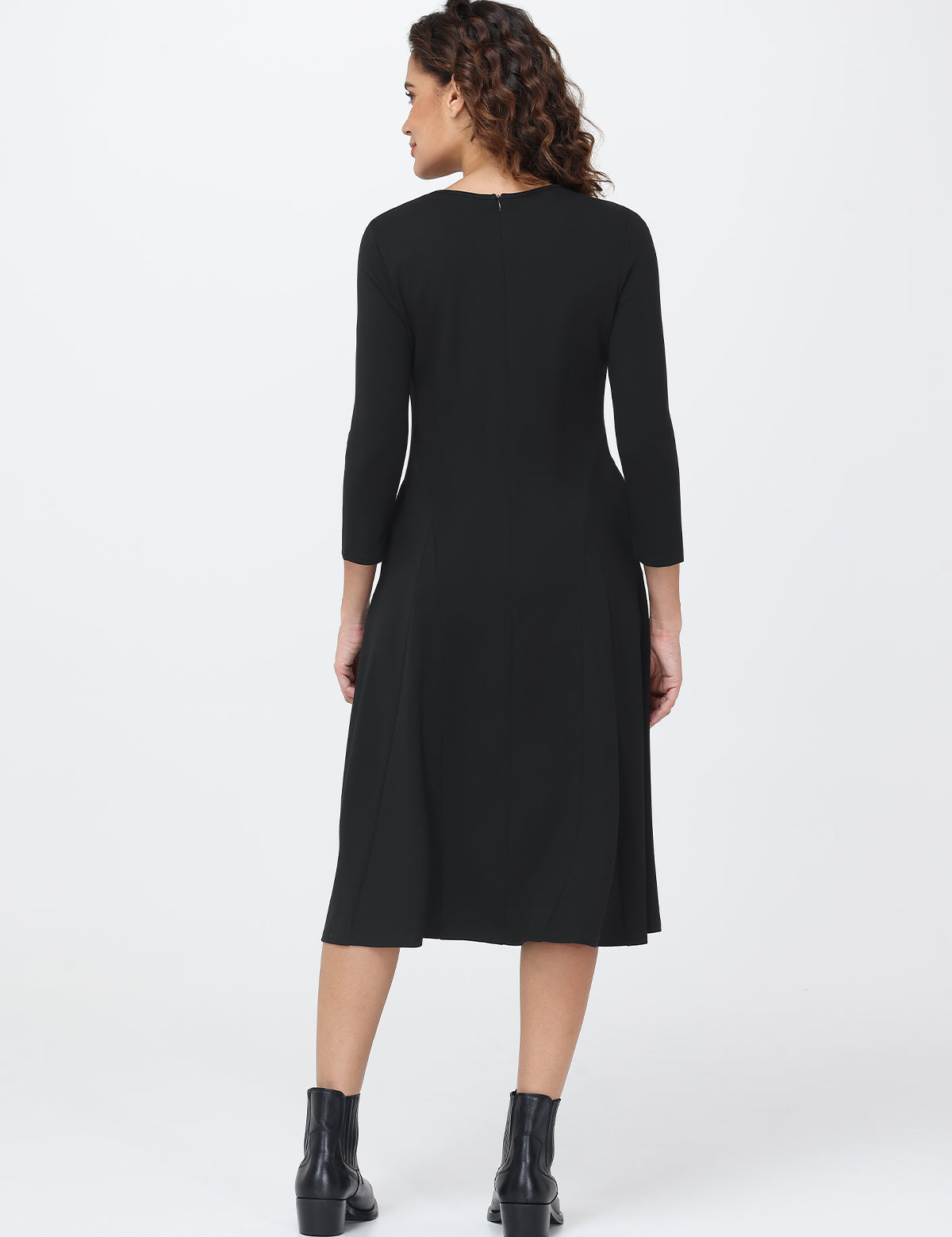 Woman wearing a black dress with long sleeves on a white background