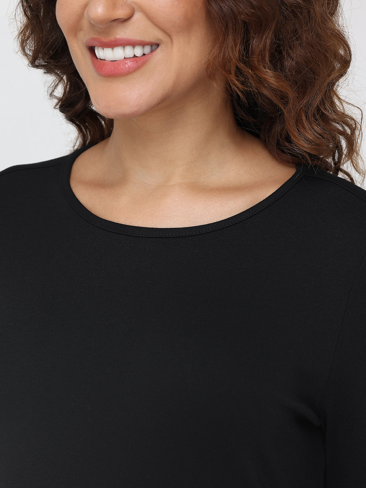 Close-up of a person wearing a black shirt with a neutral background