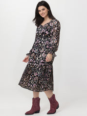 Woman wearing a floral dress with long sleeves and burgundy boots on a white background