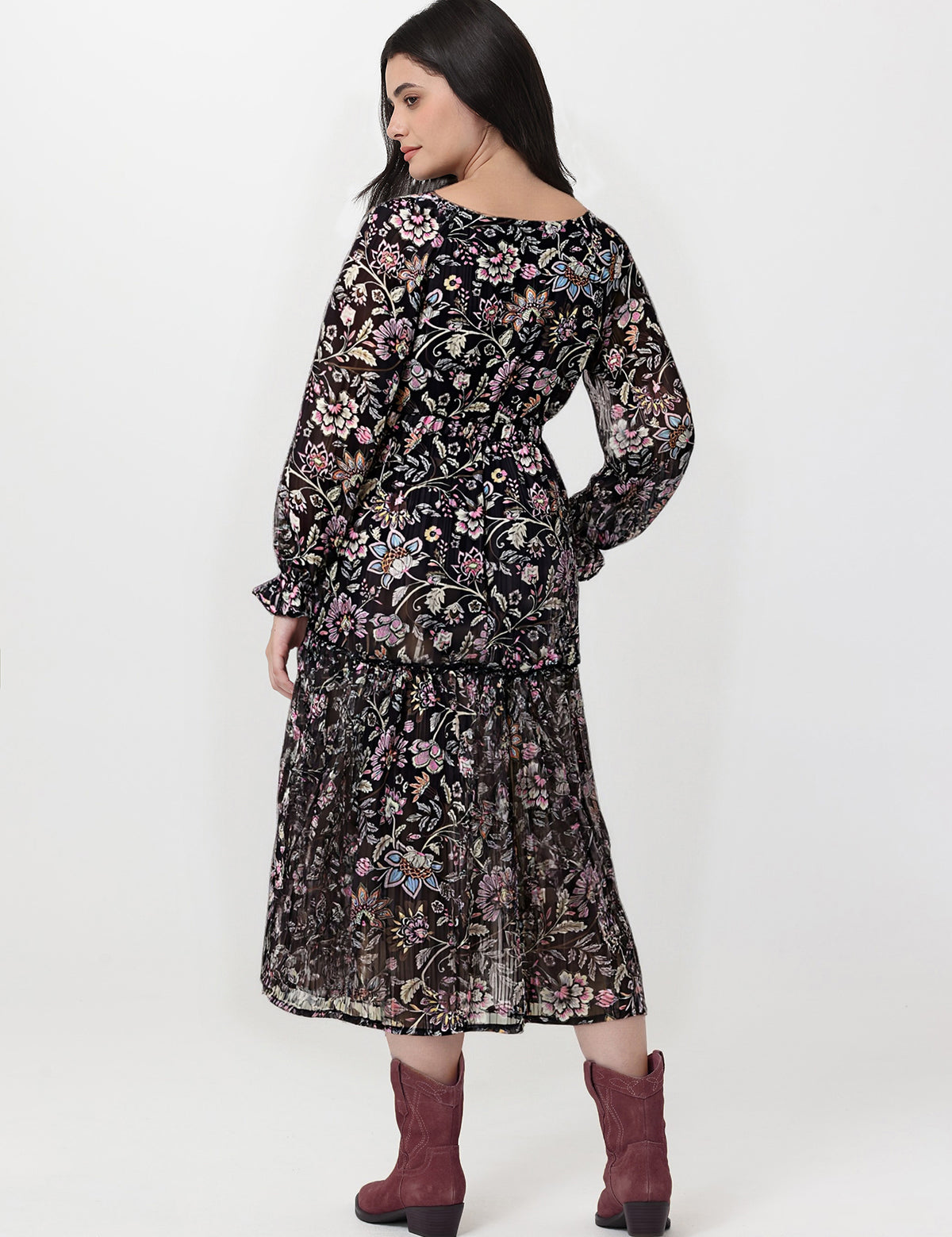 Woman wearing a black floral dress with maroon boots on a white background