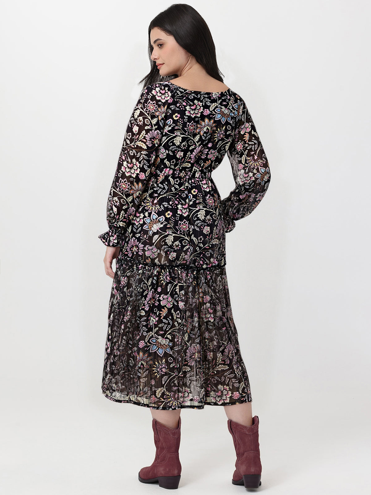 Woman wearing a black floral dress with maroon boots on a white background