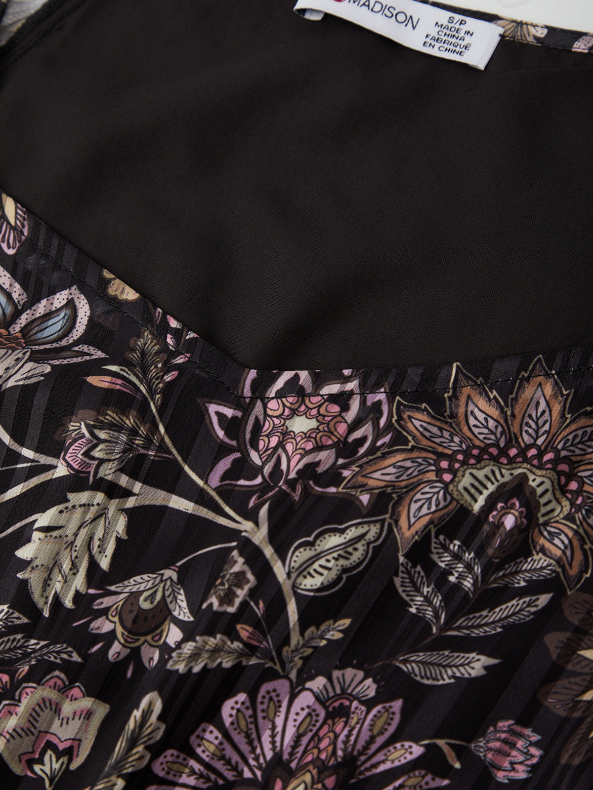 Close-up of a black fabric with floral patterns and a visible label.