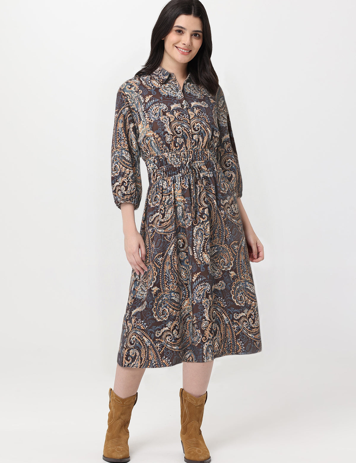 Woman wearing a patterned dress with brown boots on a white background