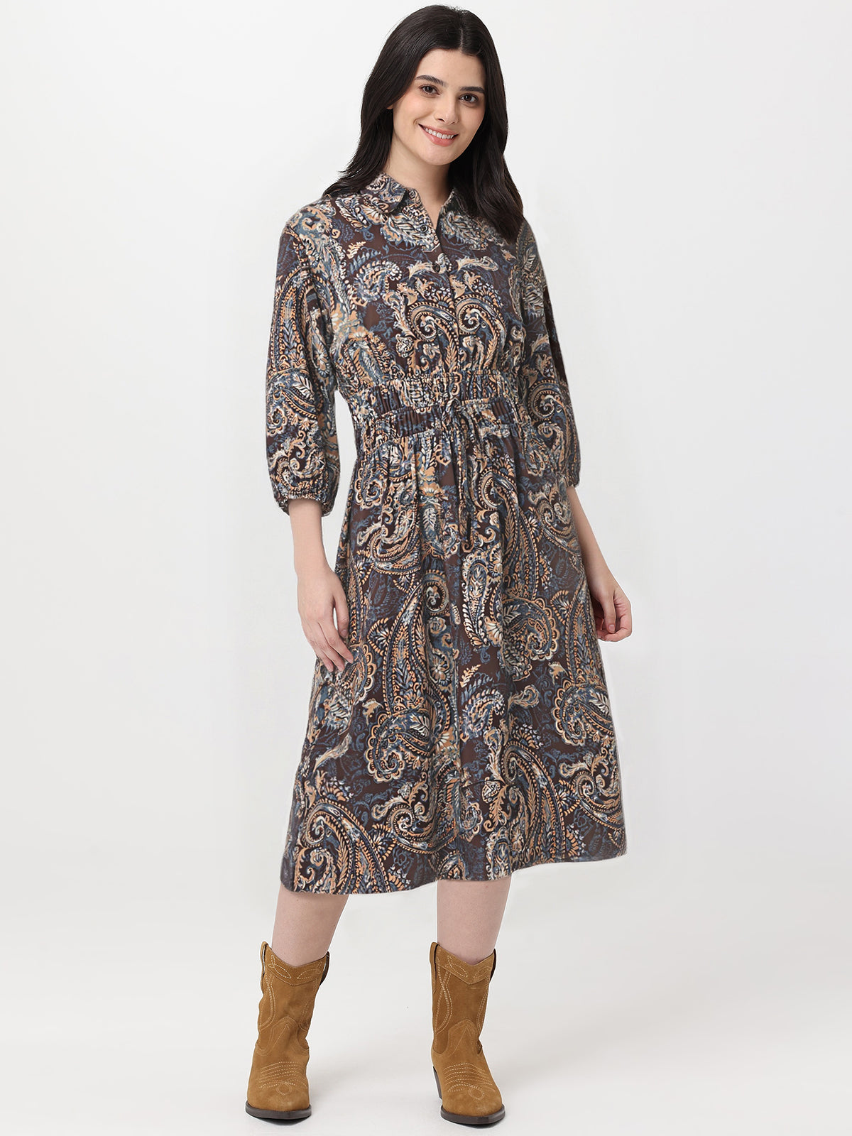 Woman wearing a patterned dress with brown boots on a white background