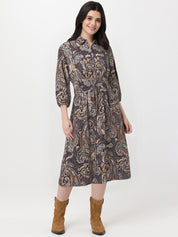 Woman wearing a patterned dress with brown boots on a white background