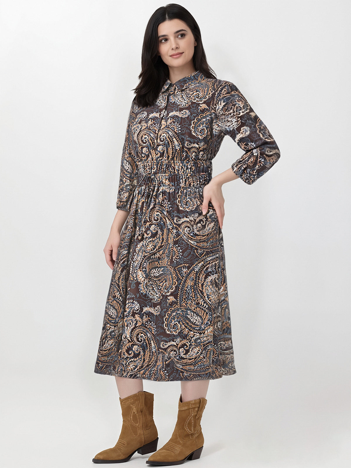 Woman wearing a patterned dress with brown boots on a white background