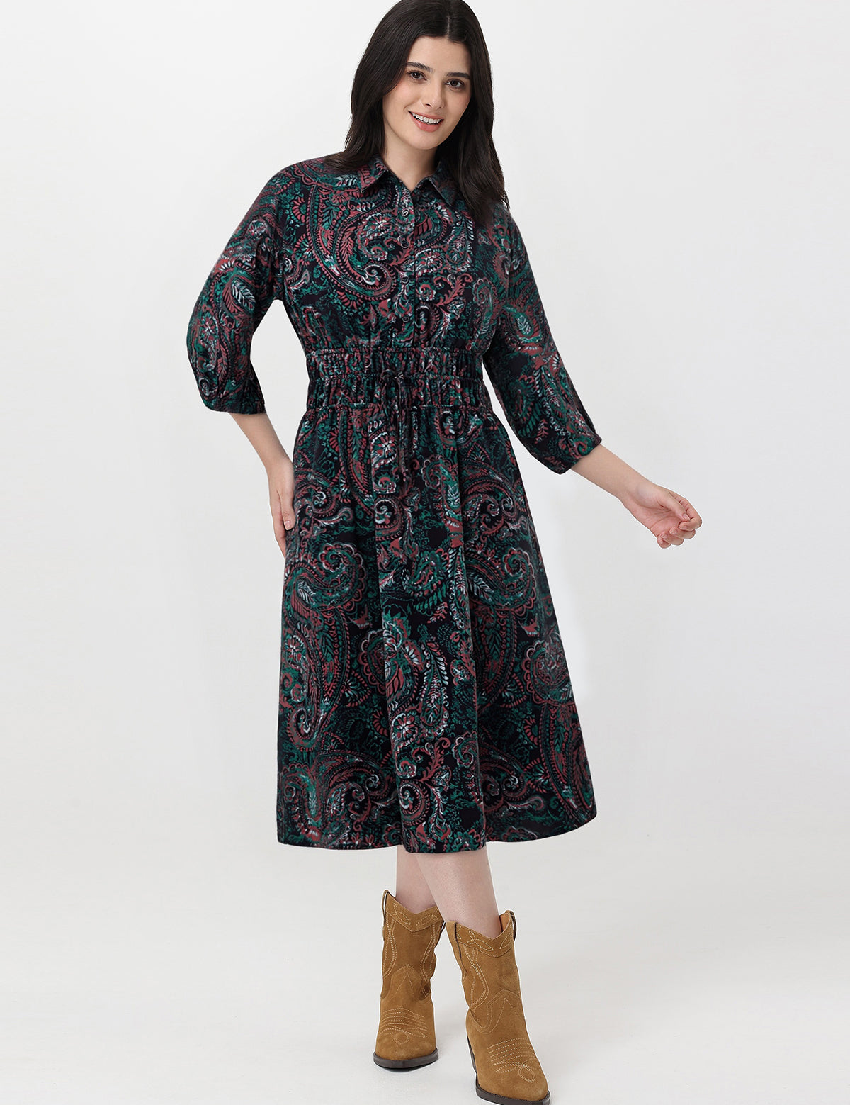 Woman wearing a patterned dress with brown boots on a white background