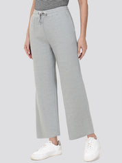 Person wearing gray wide-leg pants with a striped top and white sneakers on a light gray background