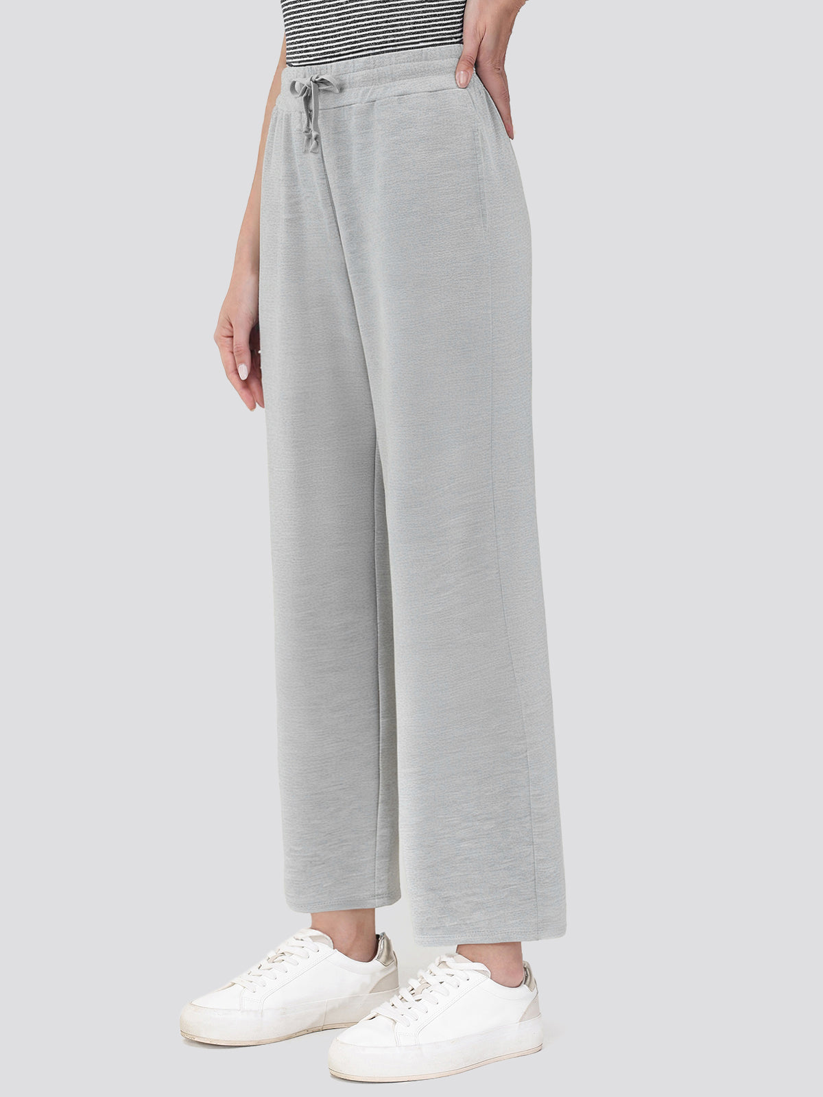 Person wearing light gray sweatpants with a white background