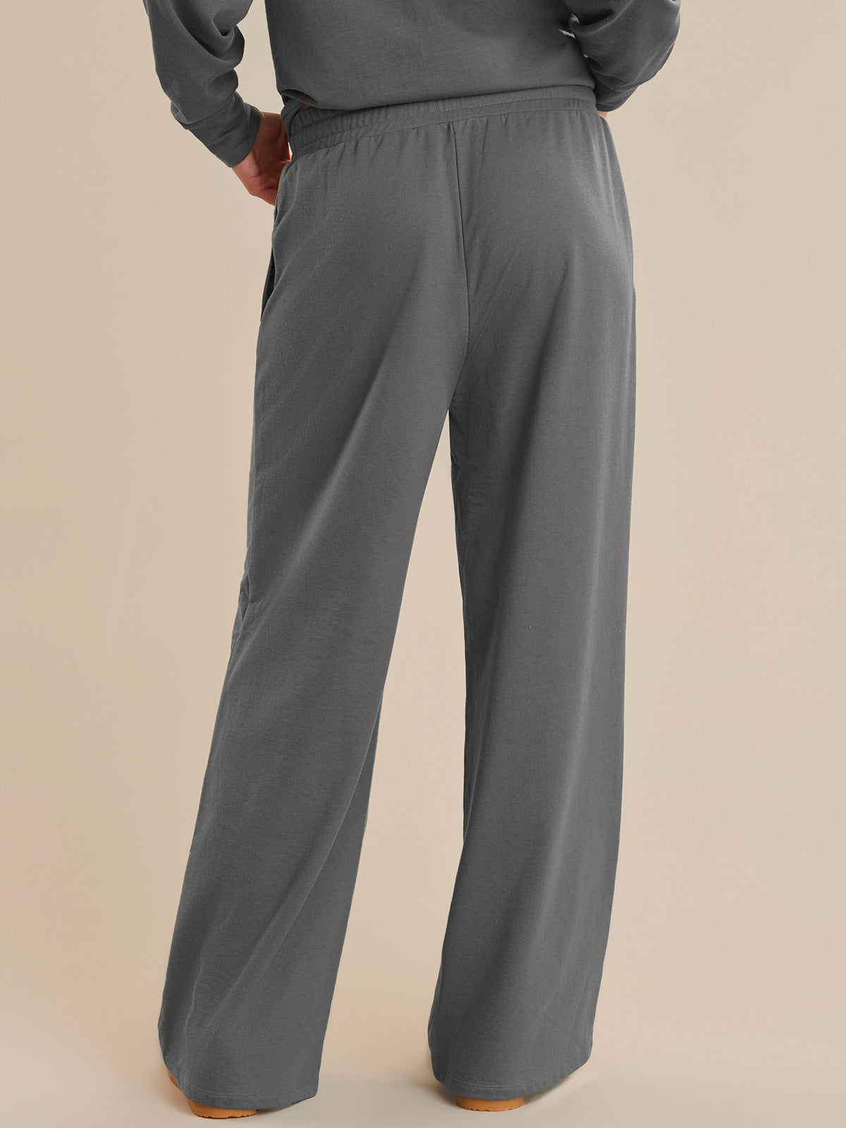 Gray sweatpants worn by a person on a beige background