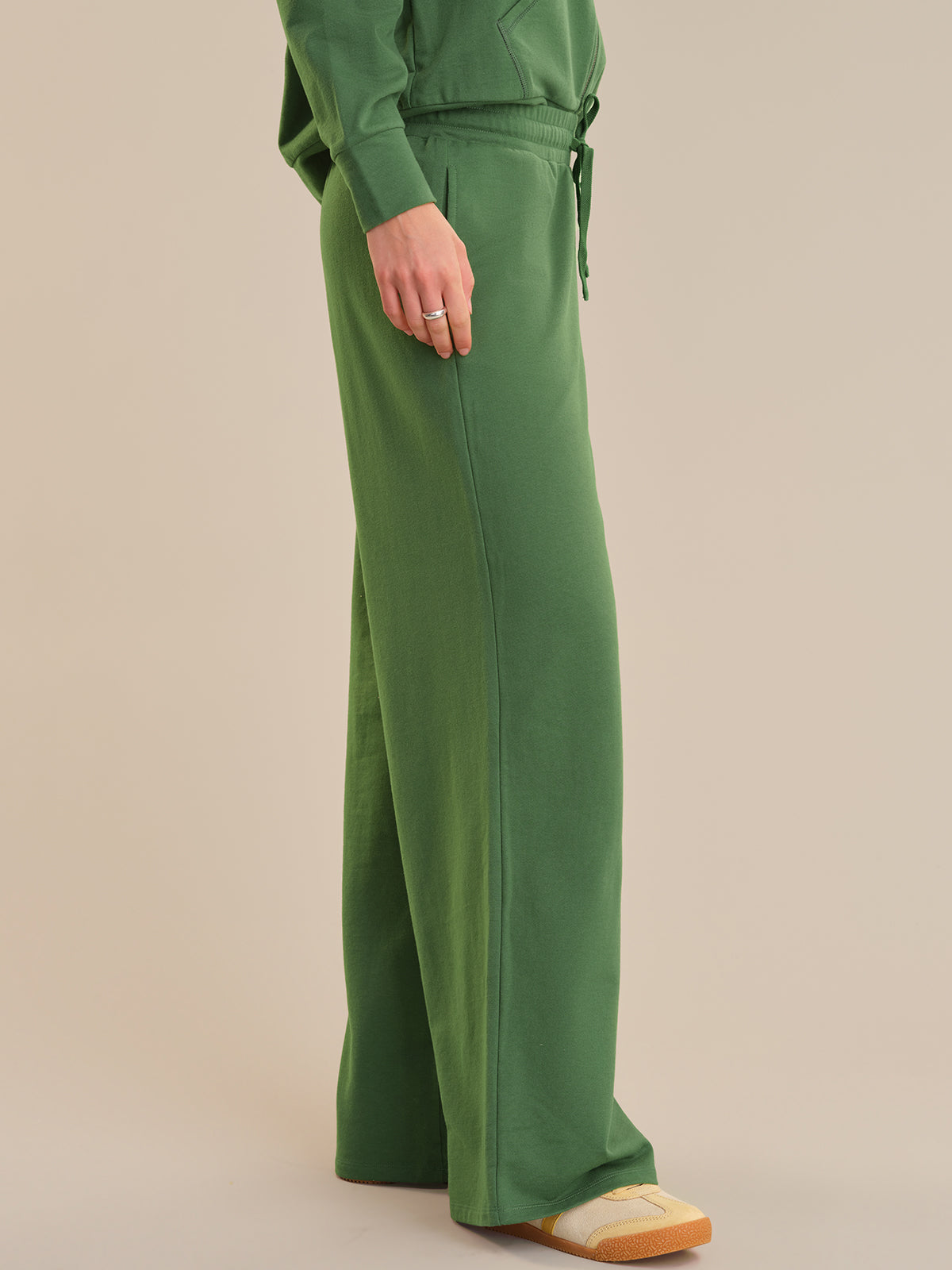 Green outfit with wide-leg pants on a beige background