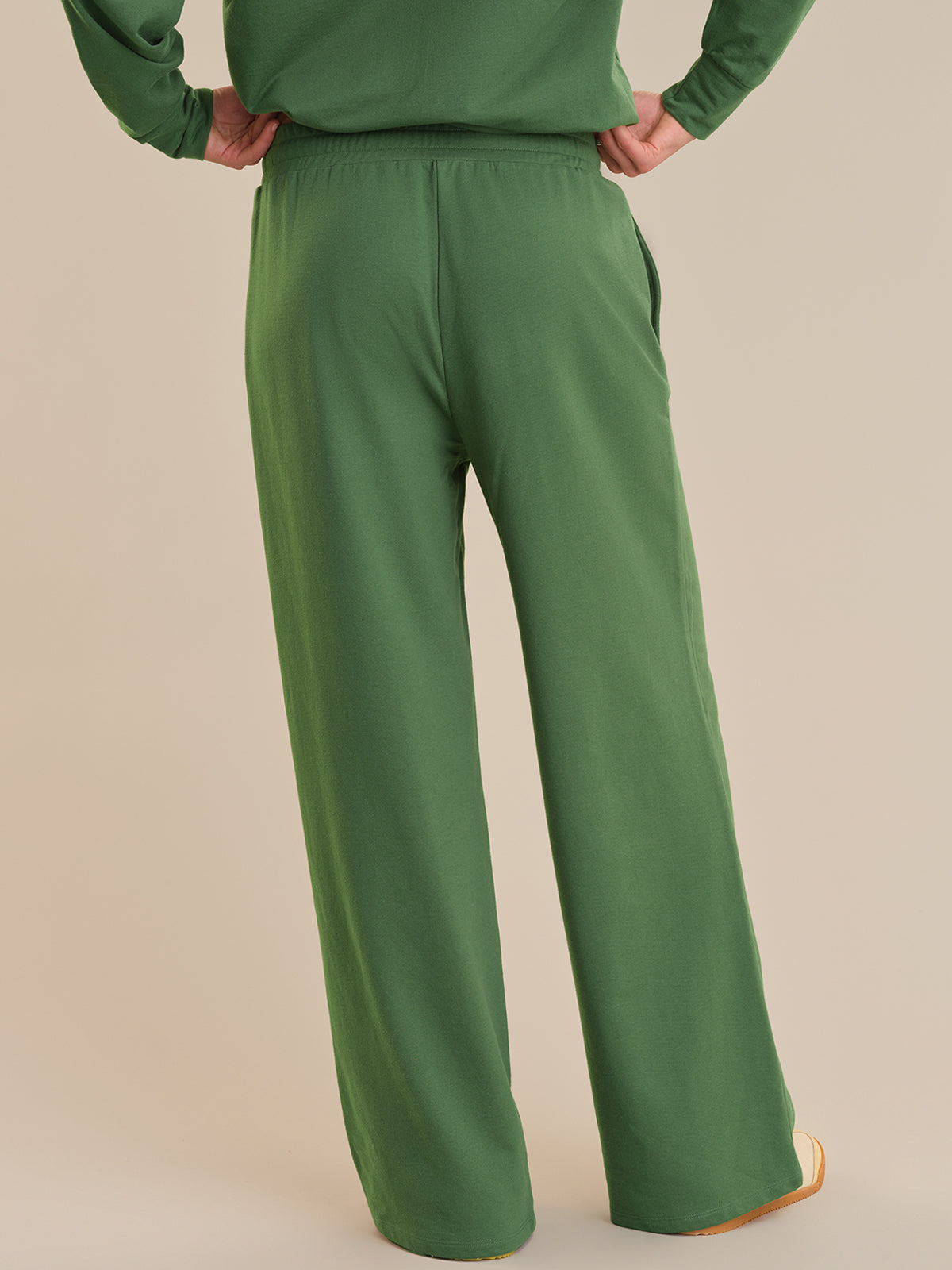 Green pants worn by a person on a beige background