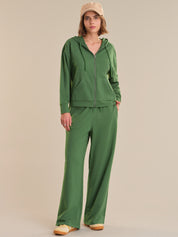 Person wearing a green tracksuit and beige cap on a beige background