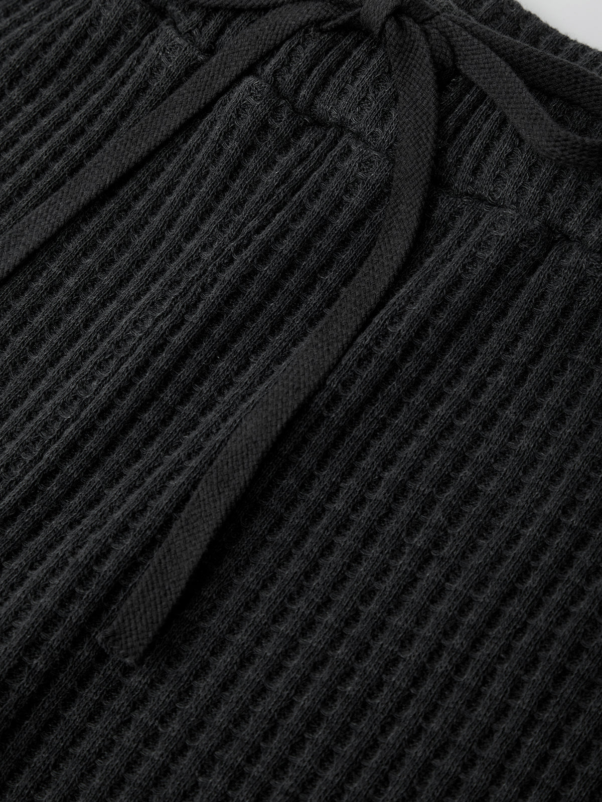 Close-up of black textured fabric with a tie detail