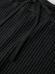 Close-up of black textured fabric with a tie detail