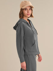 Woman wearing a gray hoodie and beige cap on a beige background