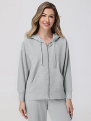 Woman wearing a gray hoodie and pants on a light gray background