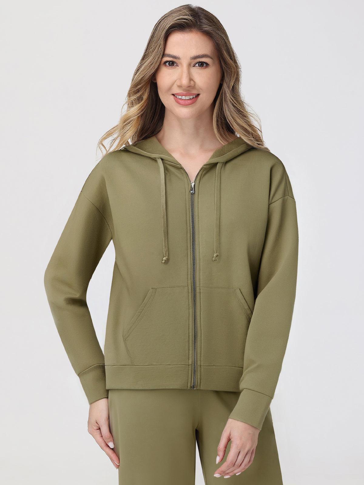 Woman wearing a green hoodie and pants on a white background