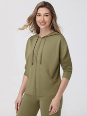 Woman wearing an olive green hoodie and leggings on a white background