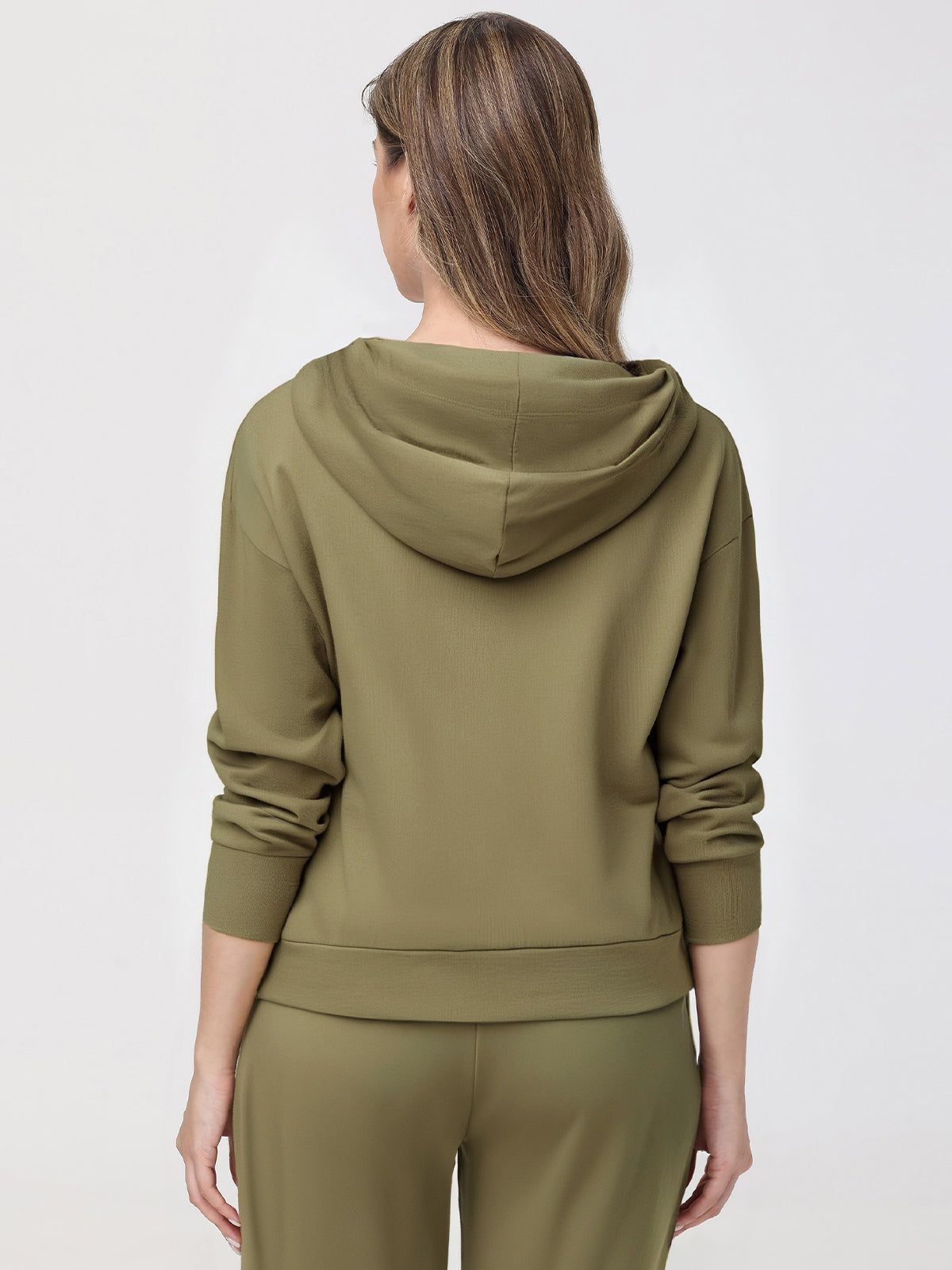 Woman wearing an olive green hoodie and pants on a white background