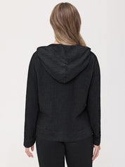 Person wearing a black textured hoodie and pants on a white background