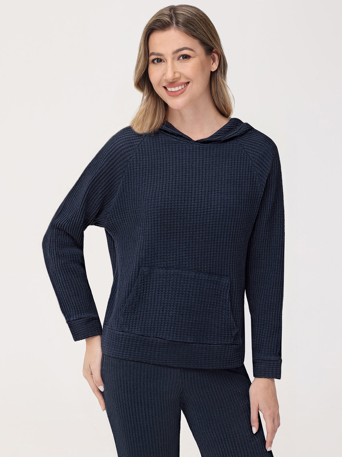 Woman wearing a navy blue hoodie and pants on a white background