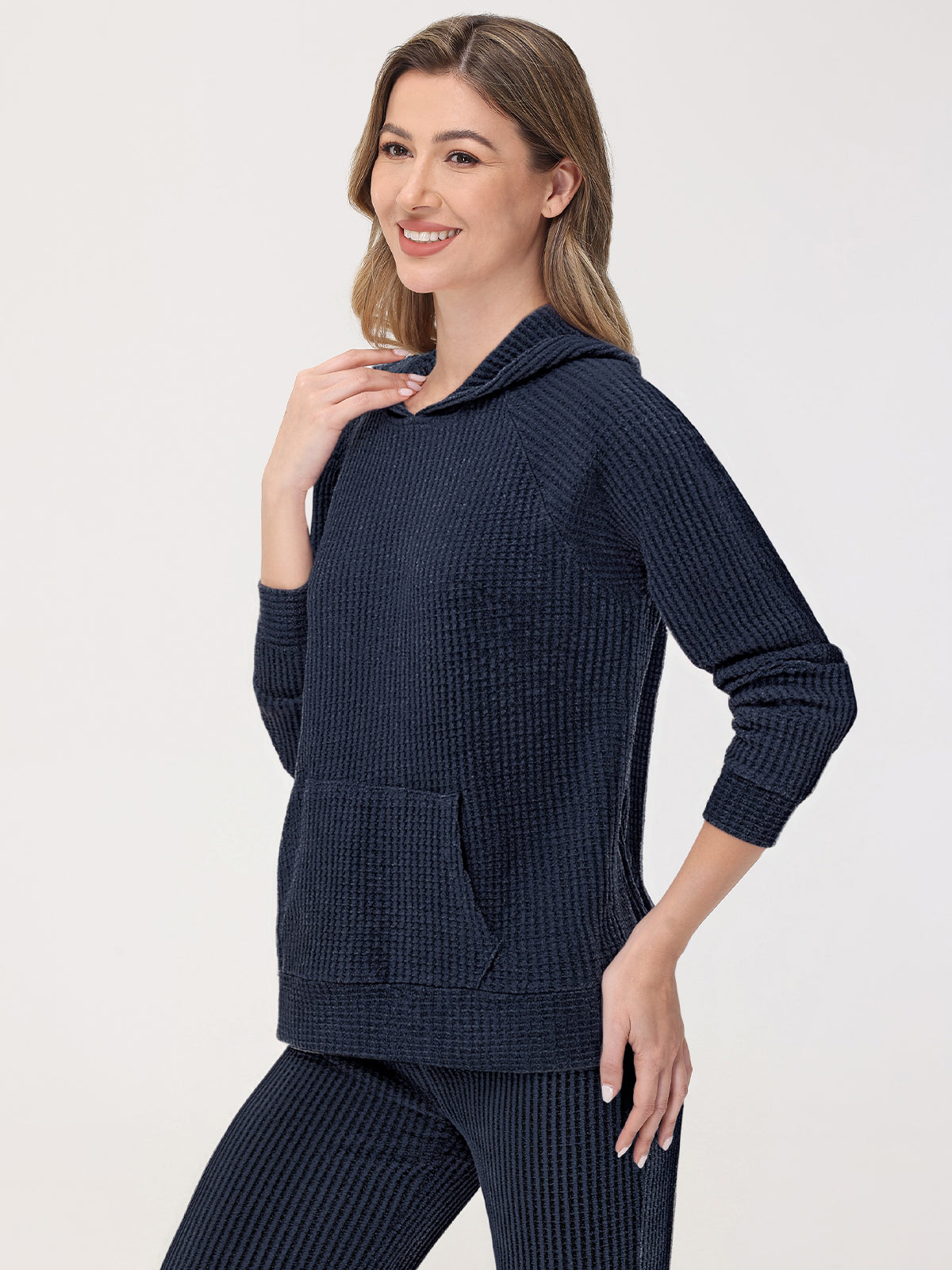 Woman wearing a navy blue hooded sweater with a white background