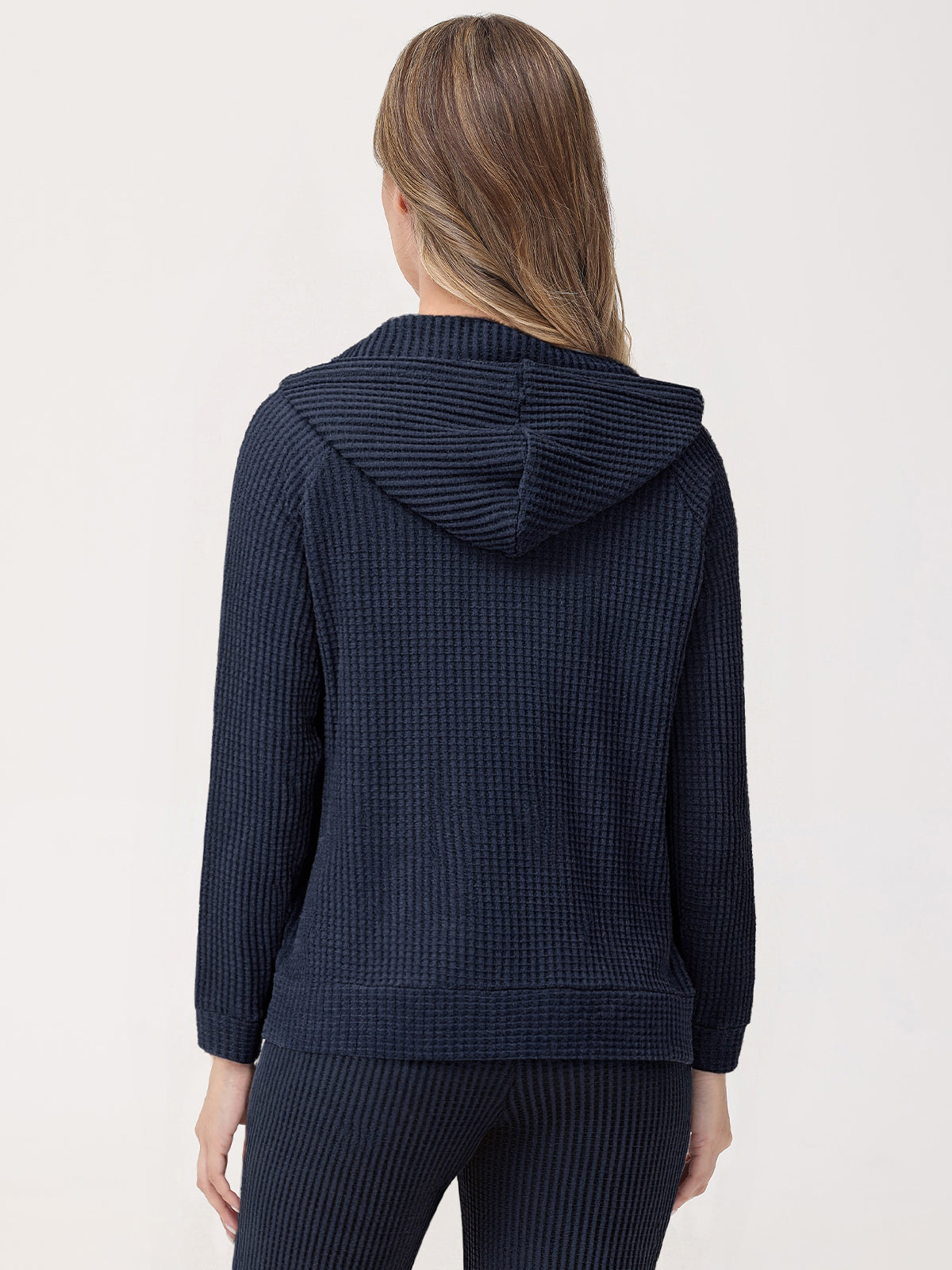 Person wearing a navy blue textured hoodie and pants on a light background