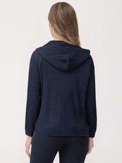 Person wearing a navy blue textured hoodie and pants on a light background