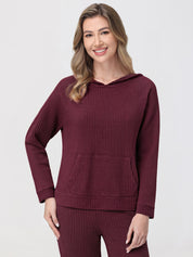 Woman wearing a burgundy waffle-textured hoodie and pants on a light gray background