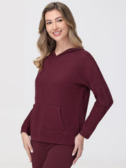 Woman wearing a burgundy waffle knit hoodie on a white background
