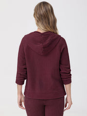 Person wearing a burgundy waffle knit hoodie and pants on a light gray background