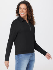 Woman wearing a black long-sleeve top with a collar and blue jeans on a white background